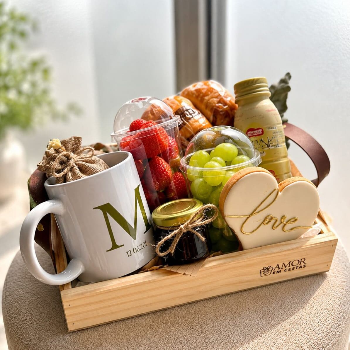 Cesta café da manhã com frutas frescas, pães artesanais e caneca personalizada 'M'.